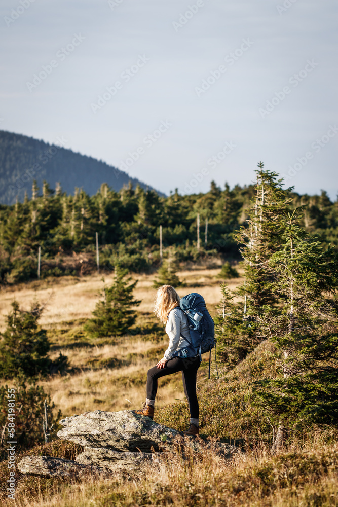 Woman hiking in mountains. Tourist with backpack walks on trekking trail. Adventure in nature Woman hiking in mountains. Tourist with backpack walks on trekking trail. Adventure in nature