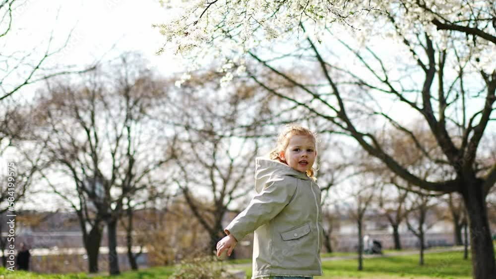 Happy little girl jumping under tree in spring park in Prague, Europe Happy little girl jumping under tree in spring park in Prague, Europe