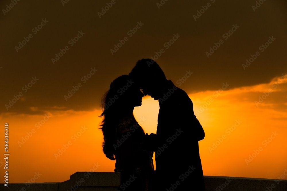 a romantic couple shadow close to each other and the sun set in the background