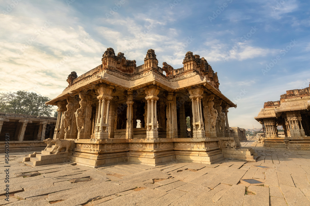 Ancient stone architecture ruins inside Vijaya Vittala temple complex at Hampi Karnataka at sunrise.