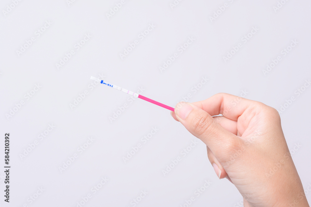 Close up woman using Ovalation (LH) test or (HCG Pregnancy test) on white background Close up woman using Ovalation (LH) test or (HCG Pregnancy test) on white background