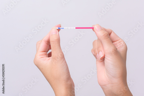 Close up woman using Ovalation (LH) test or (HCG Pregnancy test) on white background