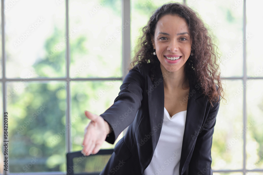 Portrait of confident and beautiful young African businesswoman standing and shaking hand with happy smiling emotion while standing in modern office. Success business concept Portrait of confident and beautiful young African businesswoman standing and shaking hand with happy smiling emotion while standing in modern office. Success business concept