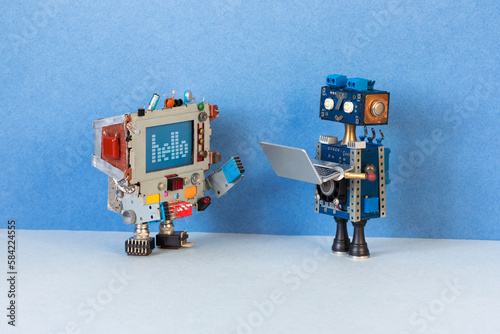 Modern and retro vintage technology concept. Toy personal computer character greets a robot holding a modern laptop.