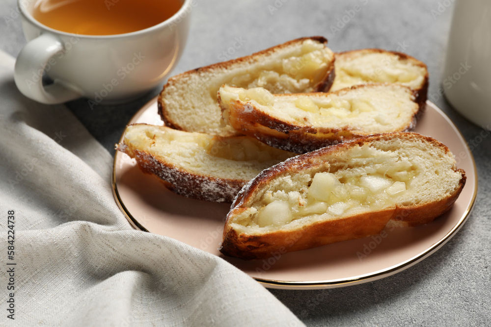Pieces of delicious yeast dough cake and tea on light gray table, closeup Pieces of delicious yeast dough cake and tea on light gray table, closeup