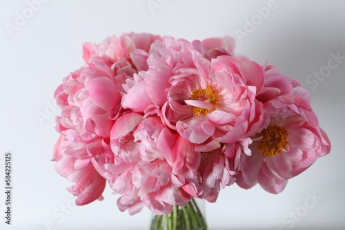 Beautiful bouquet of pink peonies in vase against white background, closeup