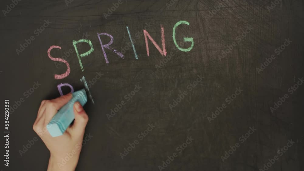 Timelapse close-up a child hand writes a spring break on a blackboard with colored chalk and draws the sun. The concept of vacation, childhood, school