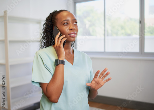 Young healthcare professional speaks on the phone wearing scrubs