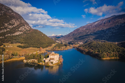 Romantic Toblino castle on the shore of the beautiful lake Toblino. Panoramic aerial view with lake and mountains. January 2023