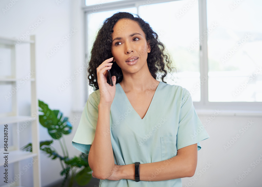 Young healthcare professional speaks on the phone wearing scrubs