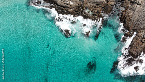 Aerial picture of blue water and rocks. Location Bremer Bay in South-west Australia. Drone view of ocean, rocks, small waves and foamy water.