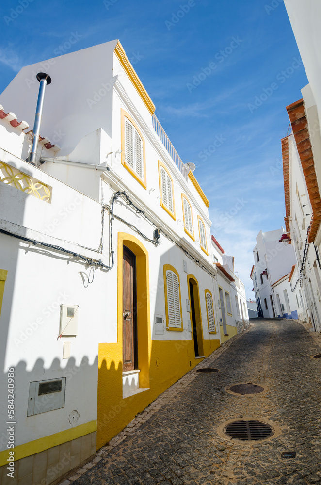 Obraz premium Narrow street of Salema. Whitewashed houses of the small authentic fishing village. Faro, Algarve, Southern Portugal.