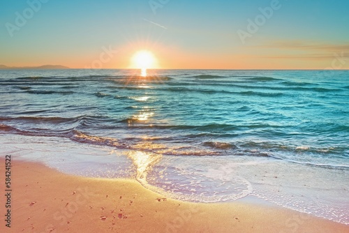 Colorful sunset viewed from the pink sea beach with soft waves