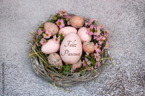 Cesta decorativa de Pascua con flores y un huevo de Pascua inscrito con el texto Felices Pascuas. photo