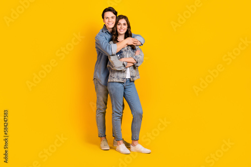 Full length photo of cute adorable young husband wife dressed denim embracing smiling isolated yellow color background © deagreez