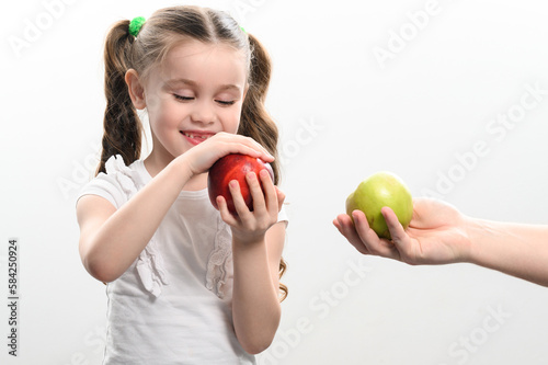 Little girl chooses between two apples, red or green apple, child's choice