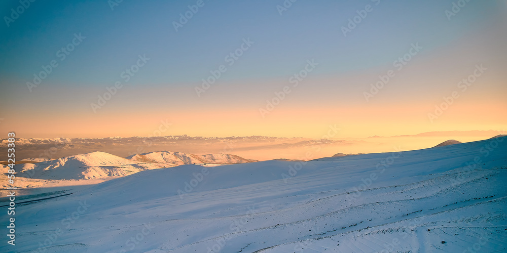 Snow covered slope of mountain in rays of evening sun. Sunset in a mountainside. Winter landscape. Erciyes mount, Kayseri, Turkiye Snow covered slope of mountain in rays of evening sun. Sunset in a mountainside. Winter landscape. Erciyes mount, Kayseri, Turkiye