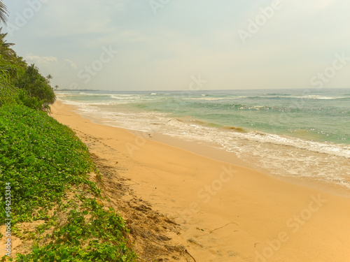 Beautiful sand beach and turquoise water. Summer holiday beach background. Ocean waves on empty tropical sand beach. Vertical background