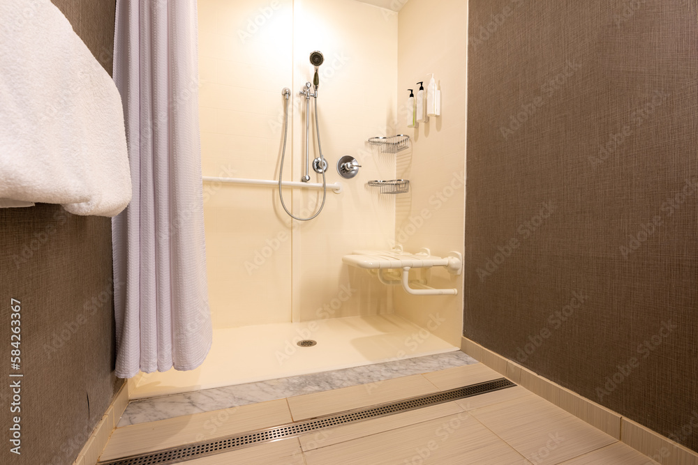 Wheelchair accessible hotel bathroom shower with tile floor and walls