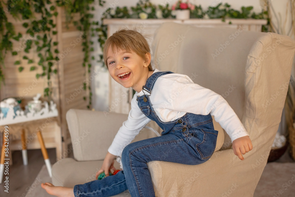 Obraz premium Sweet preschool boy in studio, playing with, egg for Easter and eating chocolate, child on Easter holiday