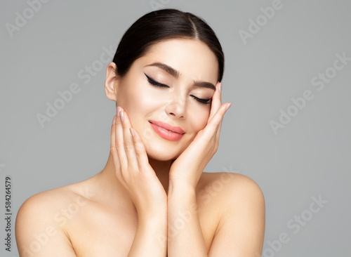 Woman Face Skin Care. Beauty Model holding Face in Hands. Beautiful Girl with Smooth Skin and Plump Lips Makeup over Gray. Facial Spa Cosmetology and Plastic Surgery