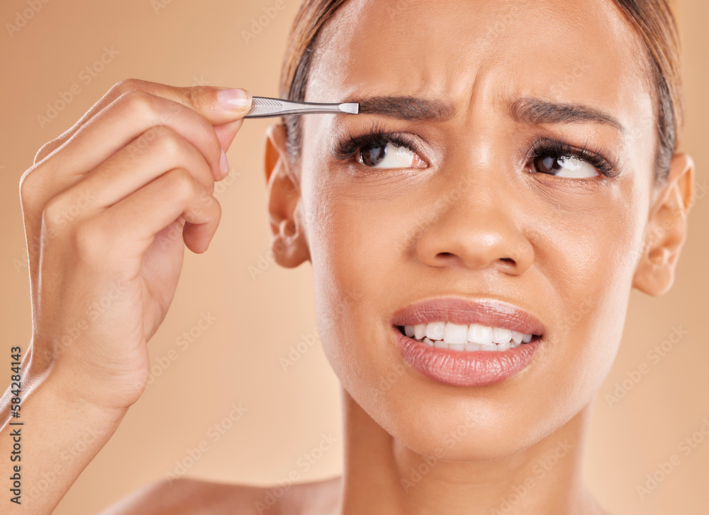 Pain, hair removal and eyebrows with woman and tweezers in studio for clean, self care and cosmetics. Facial, plucking and shape with female model on brown background for grooming and skincare Pain, hair removal and eyebrows with woman and tweezers in studio for clean, self care and cosmetics. Facial, plucking and shape with female model on brown background for grooming and skincare