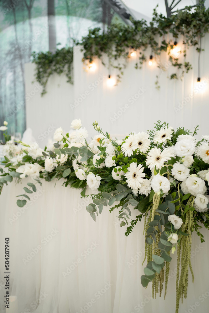 Wedding decoration table in the hall, floral arrangement. In the style vintage. Decorated dining table with flowers for guests and newlyweds, in white color.