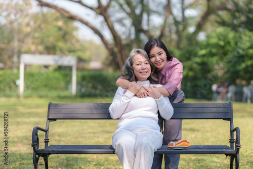 Asian mother and daughter sitting in the park happily and warmly.