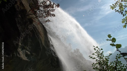 Details mountain Noasca waterfall.Water flowing. Backlight. Slow motion 4K photo