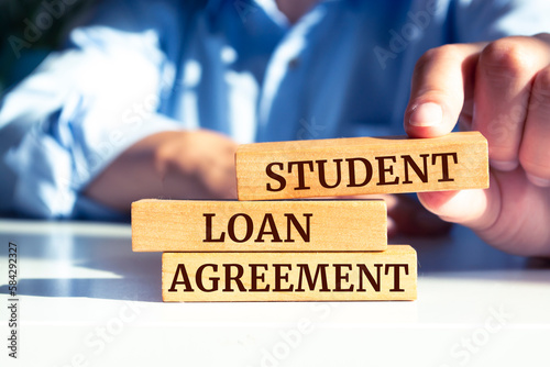 Close up on businessman holding a wooden block with "Student Loan Agreement" message