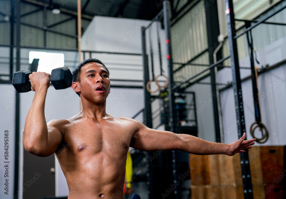Asian sport man hold dumbbell with one hand and stay on position of exercise or training in fitness gym. Asian sport man hold dumbbell with one hand and stay on position of exercise or training in fitness gym.