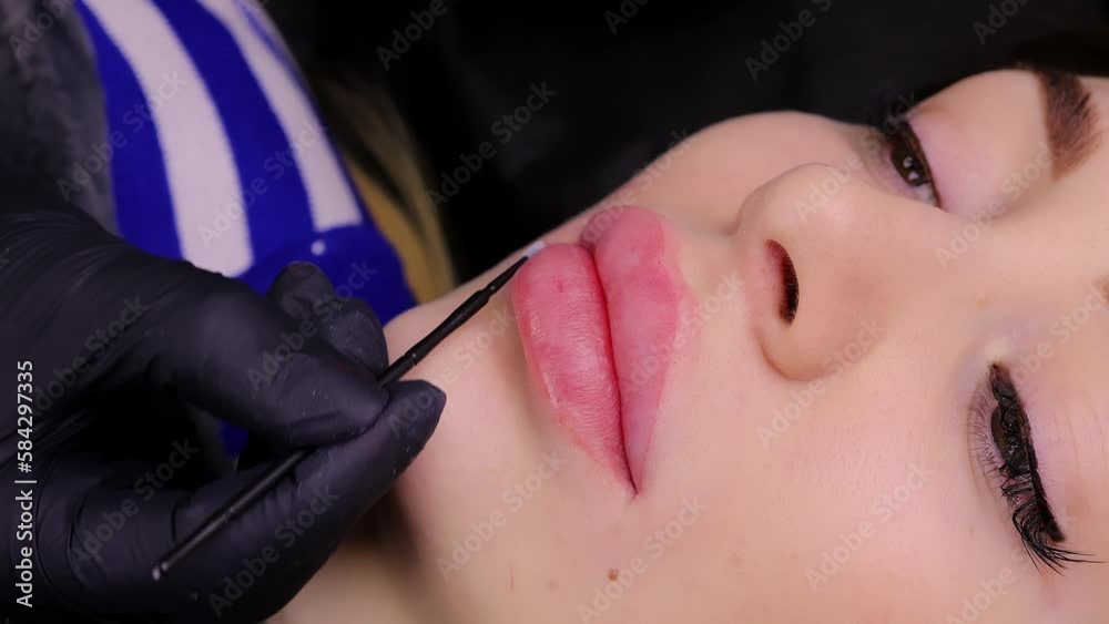 The master evenly applies anesthesia to the model's lips after the first pass of permanent makeup. High quality 4k footage The master evenly applies anesthesia to the model's lips after the first pass of permanent makeup. High quality 4k footage
