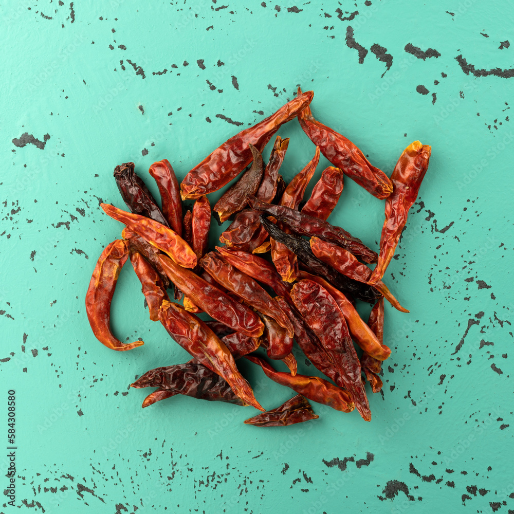 Overhead view of a pile of dehydrated Vietnamese chili peppers on a green and black countertop. Overhead view of a pile of dehydrated Vietnamese chili peppers on a green and black countertop.