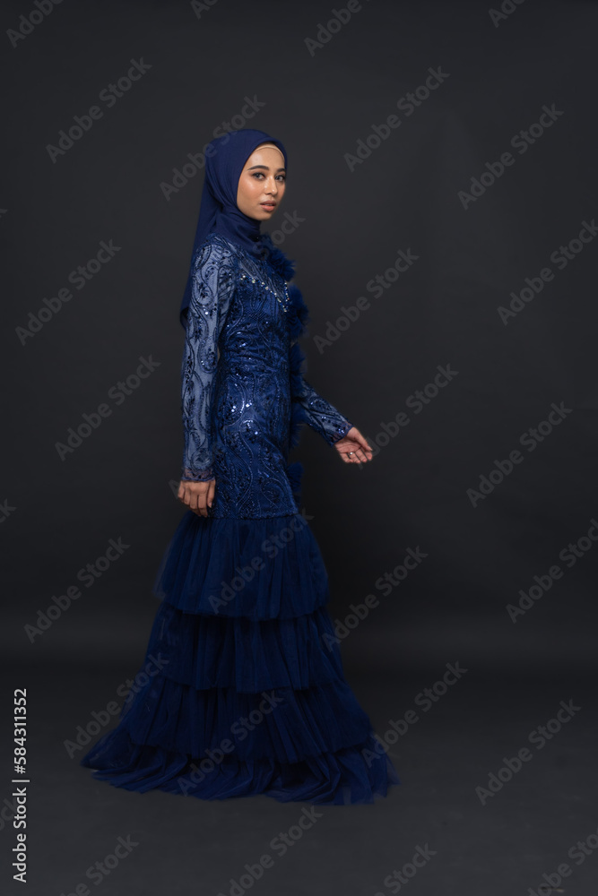 A teenager model use blue dress. She's pose in the studio indoor. She's pose in dark gray background with elegant pose. She's look like beautiful and graceful	