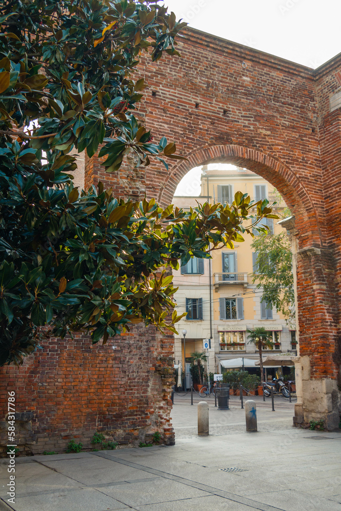 Building behind a brick arch and a tree