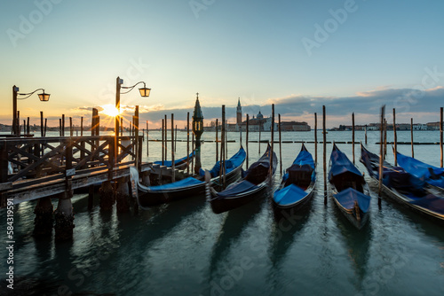 Venice  gondala's Italy. Sunrise in Venice with gondala's in the foreground on the canal and the sunrise in the backgound on blue sky. © Dave Holdham Photos