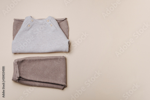 Knitted brown and beige sweater. Set of baby stuff and accessories for newborn on pastel background. Baby shower or baby care concept. Fashion newborn. Flat lay, top view