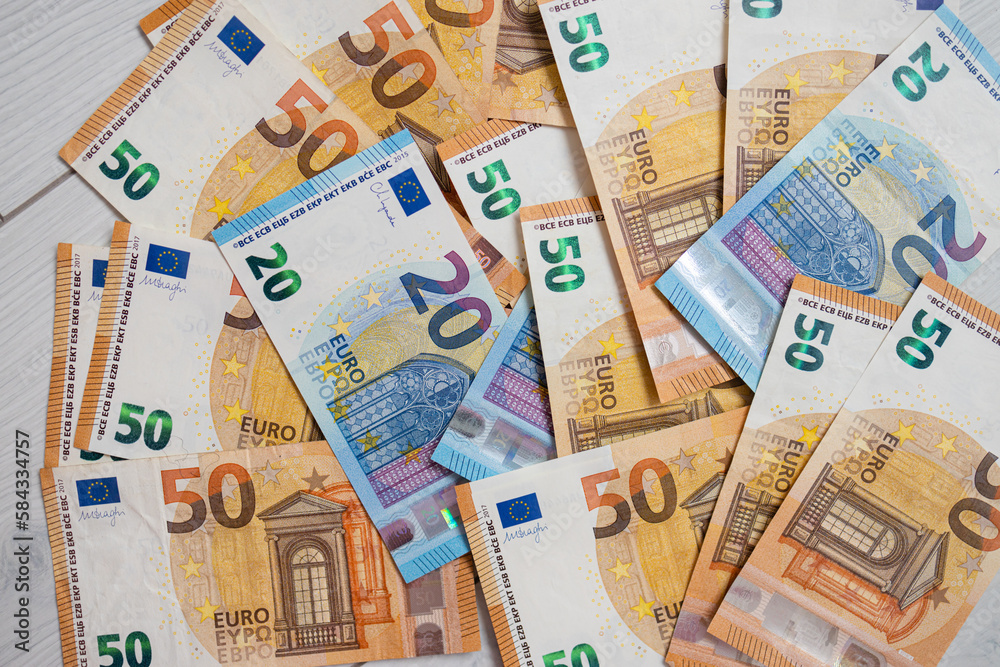 Euro money banknotes. Bundle of 50 and 20 euro bills on white wooden background. Flat lay of euros banknotes