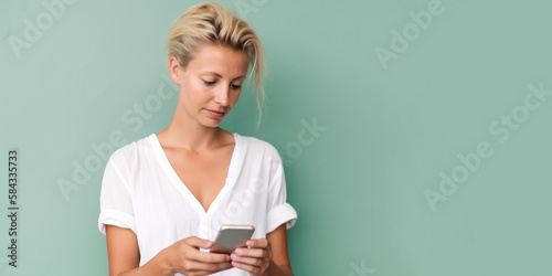 Jeune femme blonde cheveux court en train de consulter son smartphone, image avec espace pour du texte, fond neutre vert pâle - Générer par IA