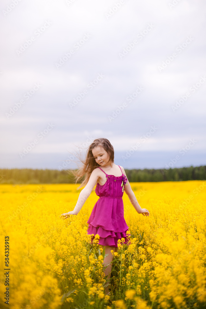 Girl in a pink dress in a field with yellow flowers Girl in a pink dress in a field with yellow flowers