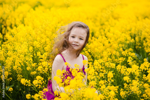 Girl in a pink dress in a field with yellow flowers
