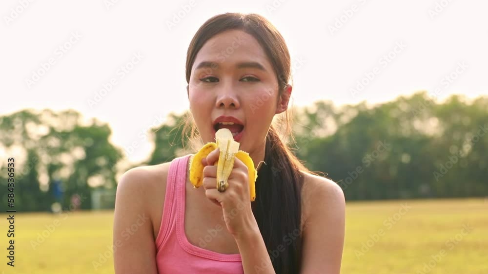 Young asian woman sits comfortably eating banana to make her stomach feel comfortable 30 minutes before exercising to help the body have nutrients to prepare for energy to exercise, not easily tired. Young asian woman sits comfortably eating banana to make her stomach feel comfortable 30 minutes before exercising to help the body have nutrients to prepare for energy to exercise, not easily tired.
