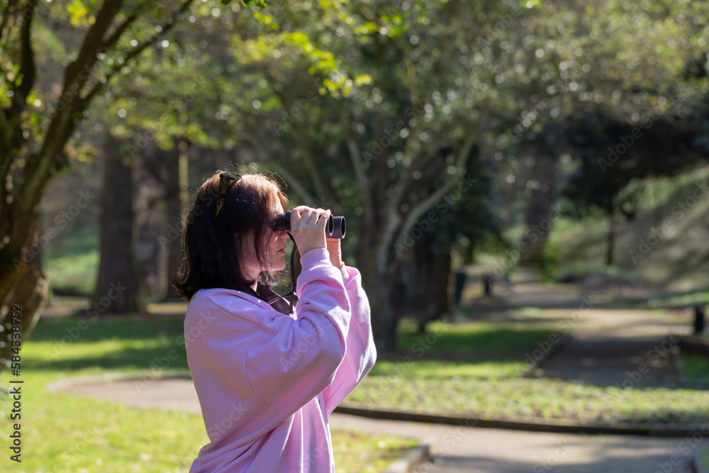 young woman with binocular in spring park