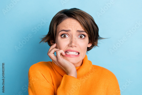 Photo portrait of lovely young lady bite fingers frightened terrible news dressed stylish orange outfit isolated on blue color background photo