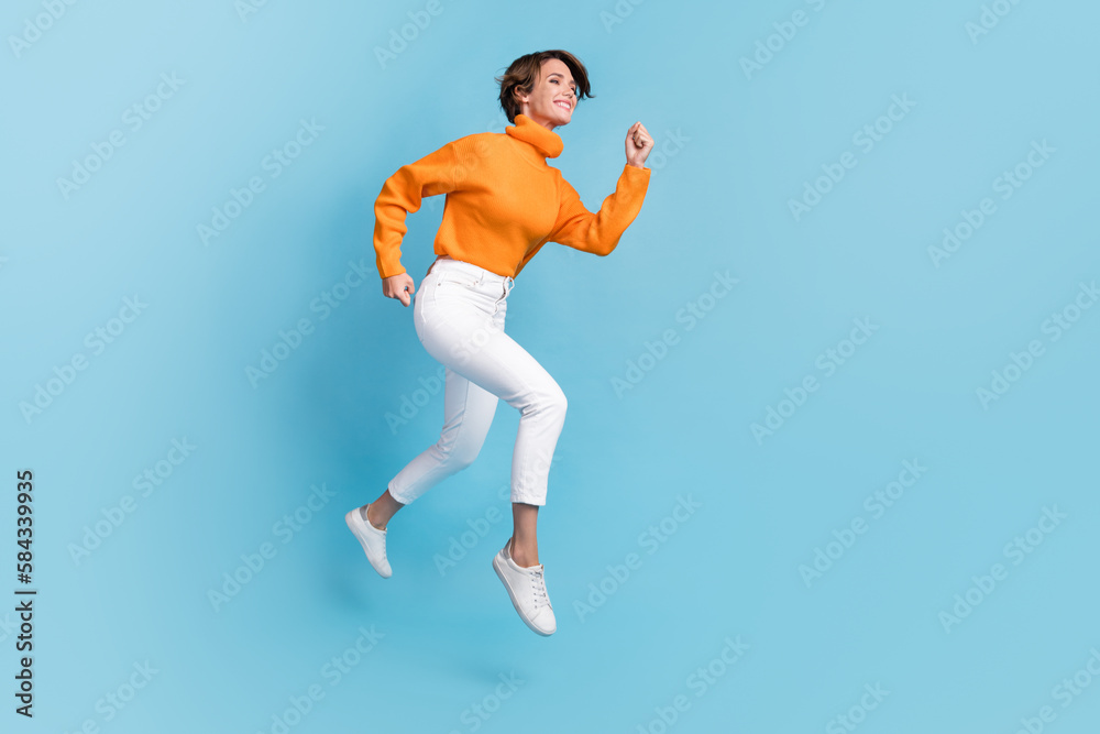 Full length photo of lovely young lady running fast rush speed shopping dressed stylish orange clothes isolated on blue color background