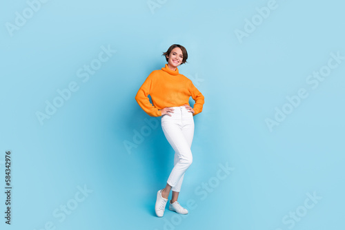 Full length photo of lovely young lady hands waist posing shopping banner dressed stylish orange garment isolated on blue color background