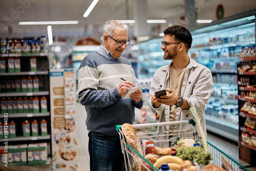 Canvas Print Young man and his senior father buying groceries at supermarket.