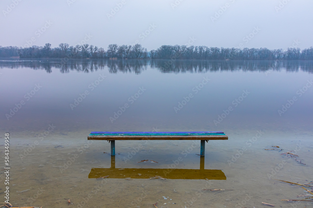 Spring flood on the river. The water level rose and flooded the bench on the shore Spring flood on the river. The water level rose and flooded the bench on the shore