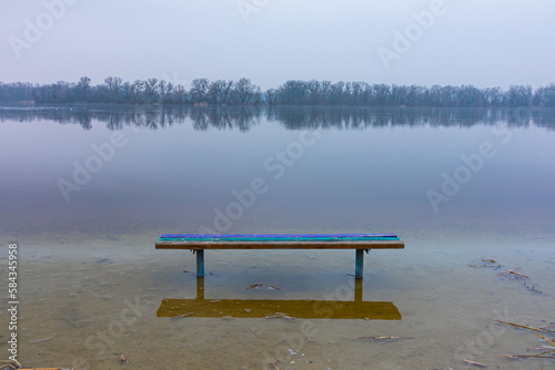 Spring flood on the river. The water level rose and flooded the bench on the shore
