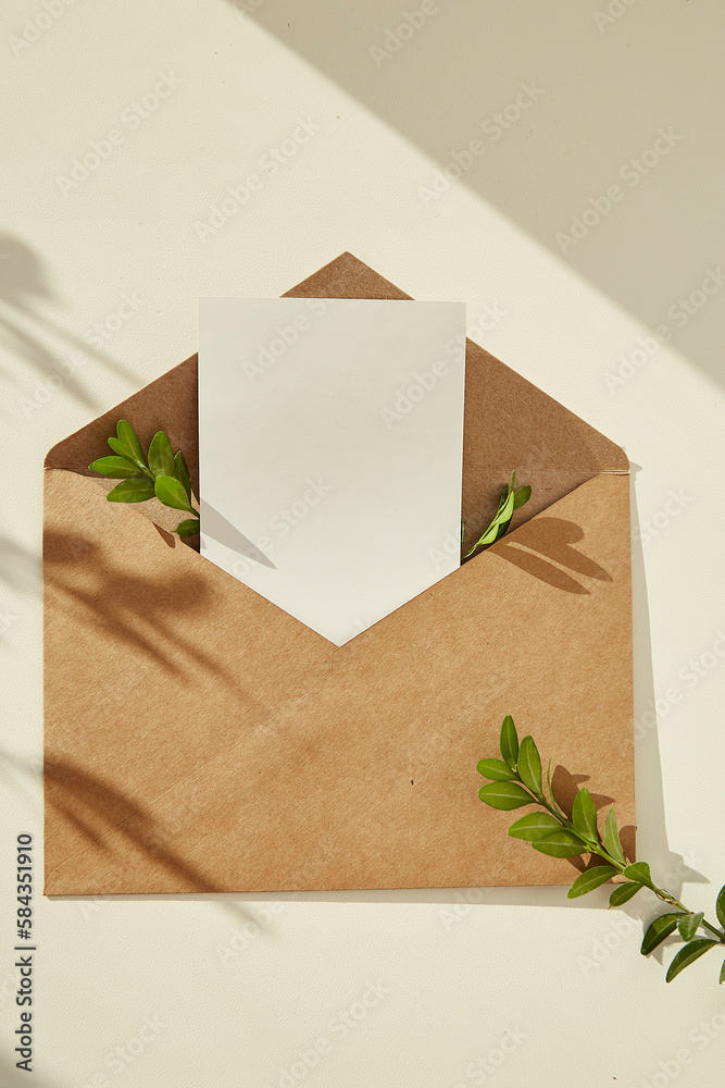 Open envelope stationery card mockup invitation,blank greeting card and green leaves under shadows - minimal composition. Place for text Open envelope stationery card mockup invitation,blank greeting card and green leaves under shadows - minimal composition. Place for text